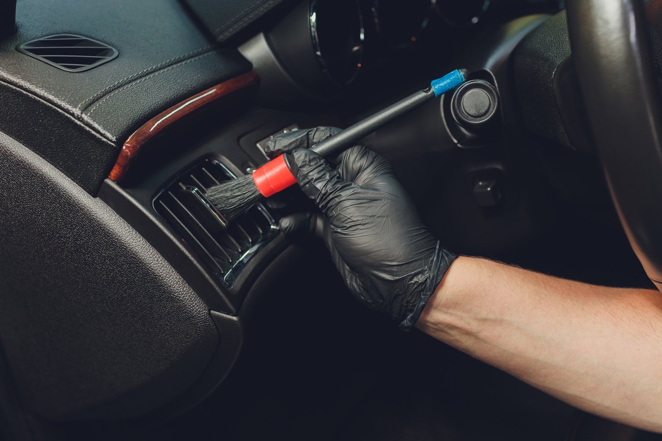 A man cleaning car with cloth and brush. Car detailing. Selective focus. Car detailing. Cleaning with brush. Worker cleaning. Brush and cleaning solution to clean.